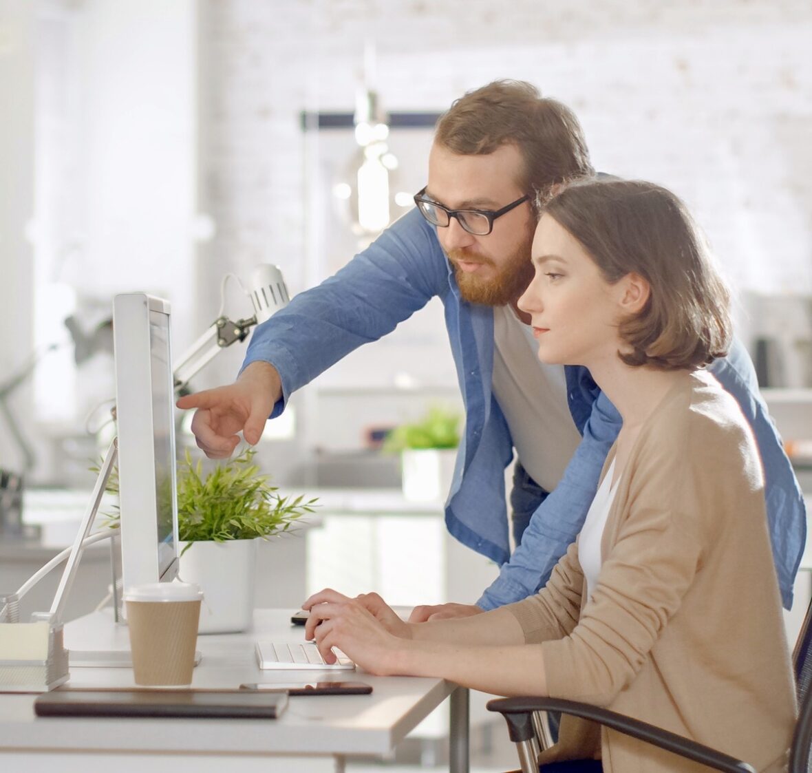 Woman and a man shopping for a garage door on a computer. Both have serious looks on their faces. They are looking online at a website belonging to Overhead Door Company of Huntsville.